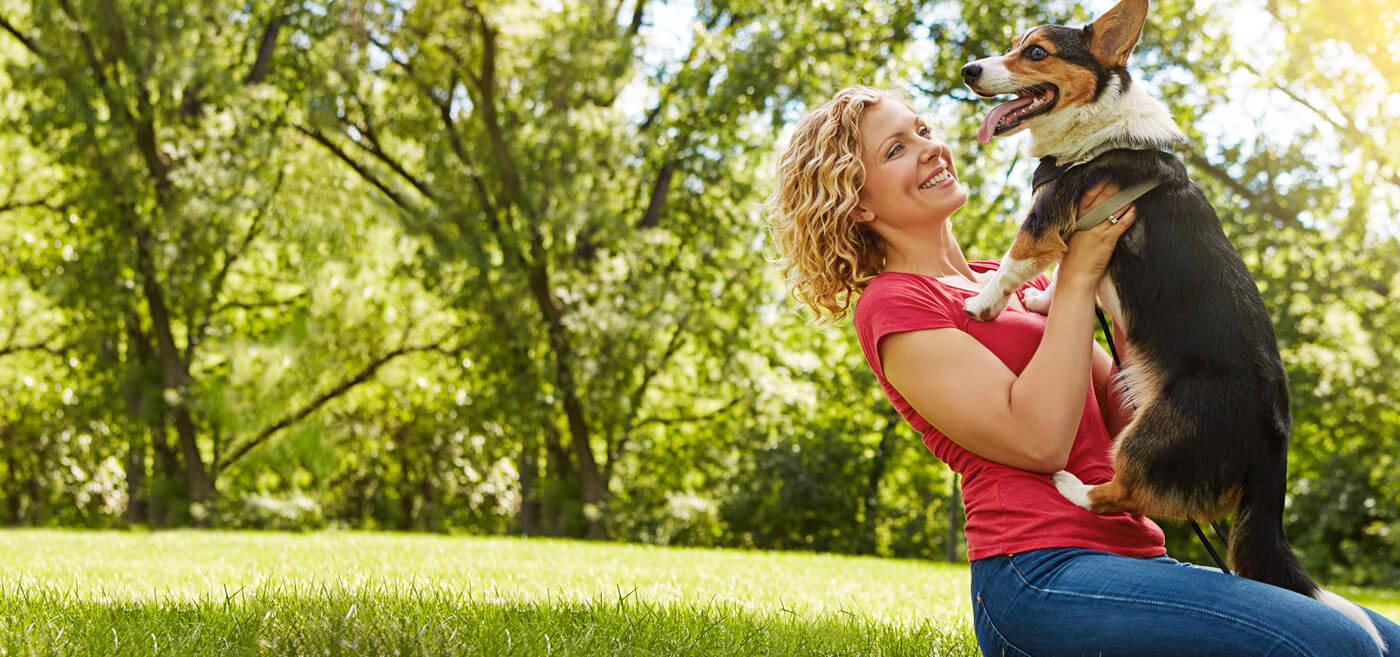 Image of a woman sitting in the grass with her dog
